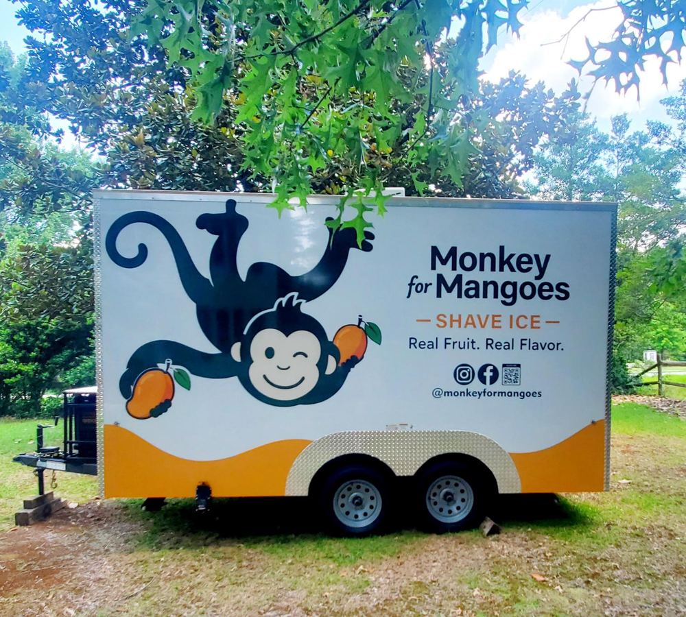 Side of the Monkey for Mangoes trailer with the swinging monkey mascot and “Real Fruit. Real Flavor.”